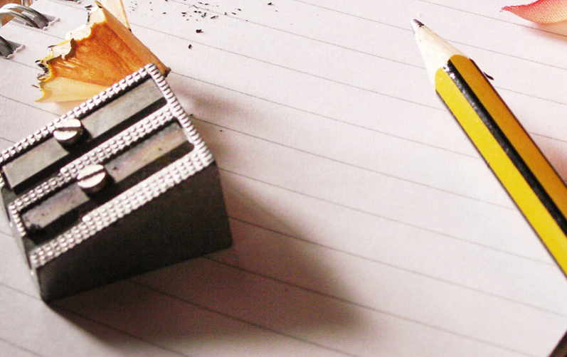 Bild på penna och pennvässare liggandes på block